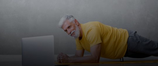 a man does yoga and fitness in the gym with a trainer online from a laptop senior male sports coach